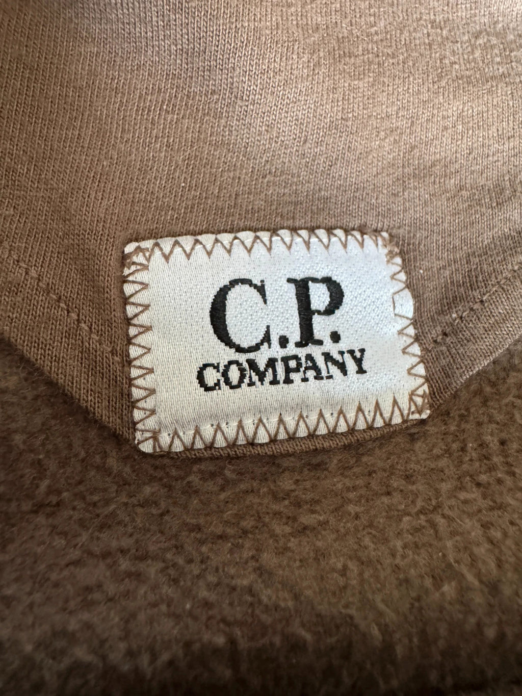 C.P. Company khaki goggle hoodie with side zip and logo detail.