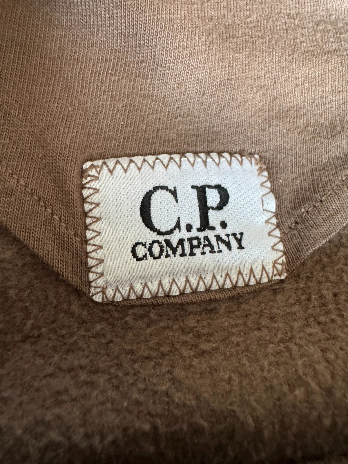 C.P. Company khaki goggle hoodie with side zip and logo detail.