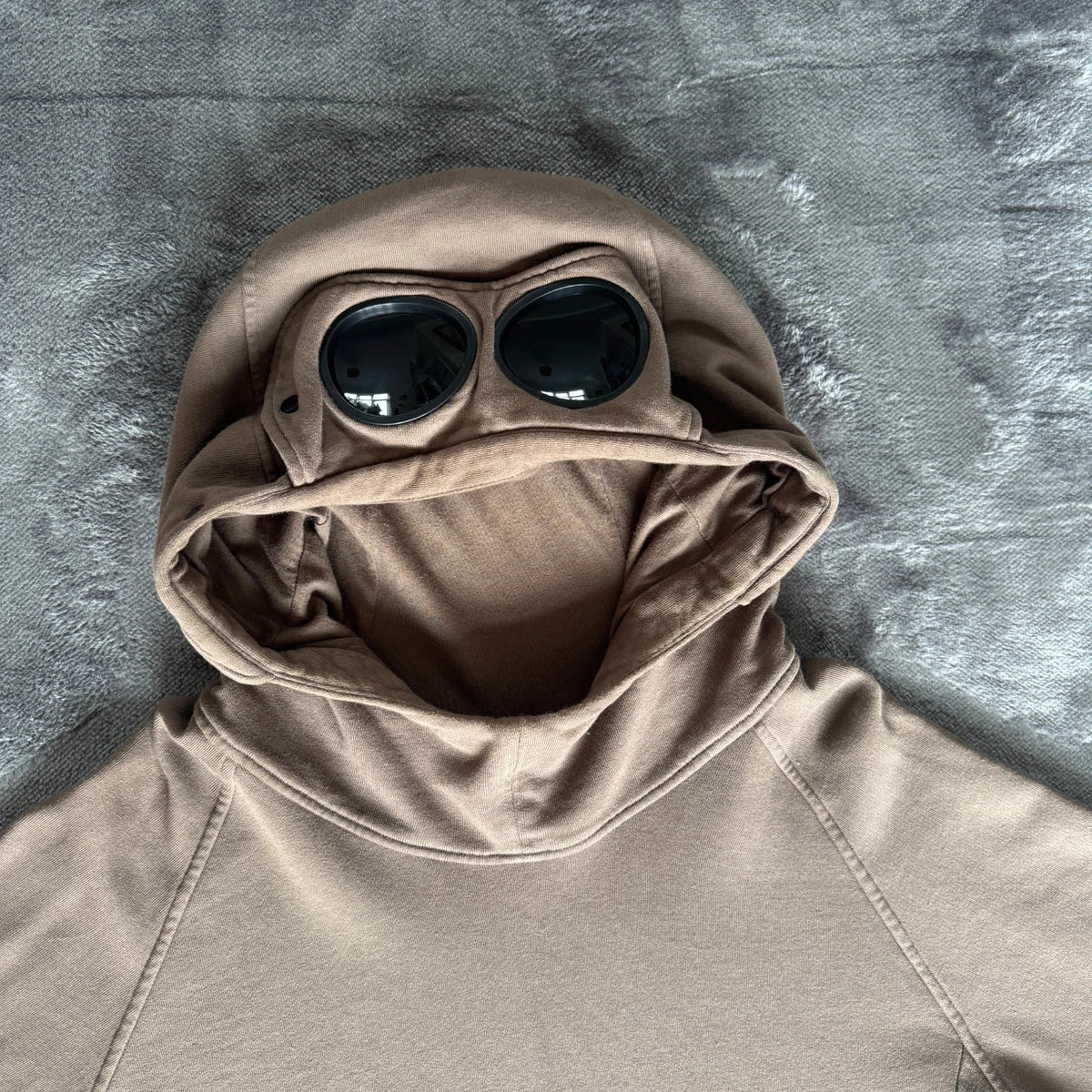 C.P. Company khaki goggle hoodie with side zip and logo detail.