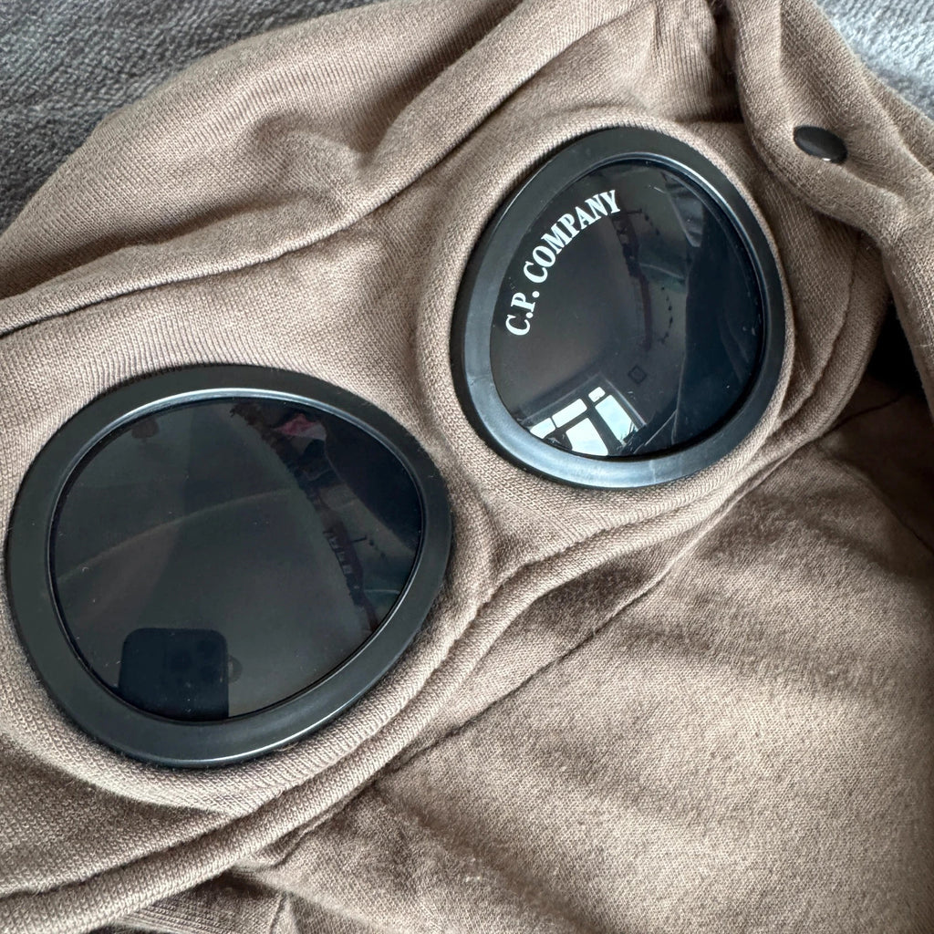 C.P. Company khaki goggle hoodie with side zip and logo detail.