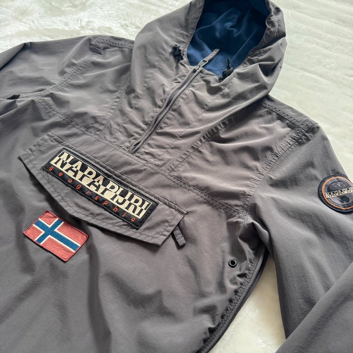 Napapijri grey pullover jacket with logo patch and ventilation zips, lightweight anorak design.