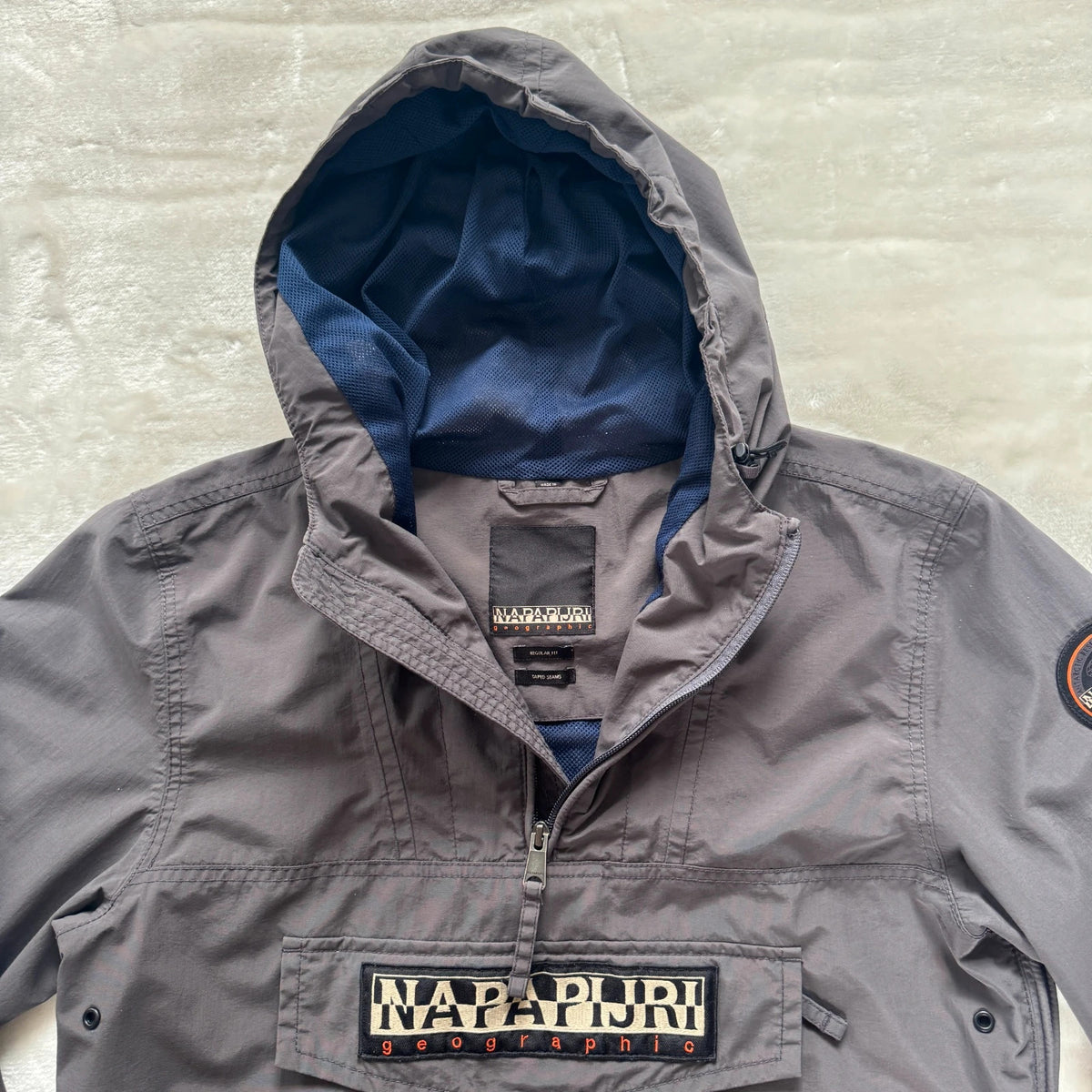 Napapijri grey pullover jacket with logo patch and ventilation zips, lightweight anorak design.