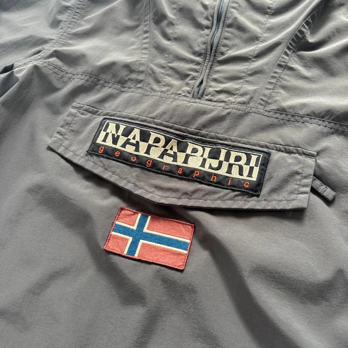 Napapijri grey pullover jacket with logo patch and ventilation zips, lightweight anorak design.