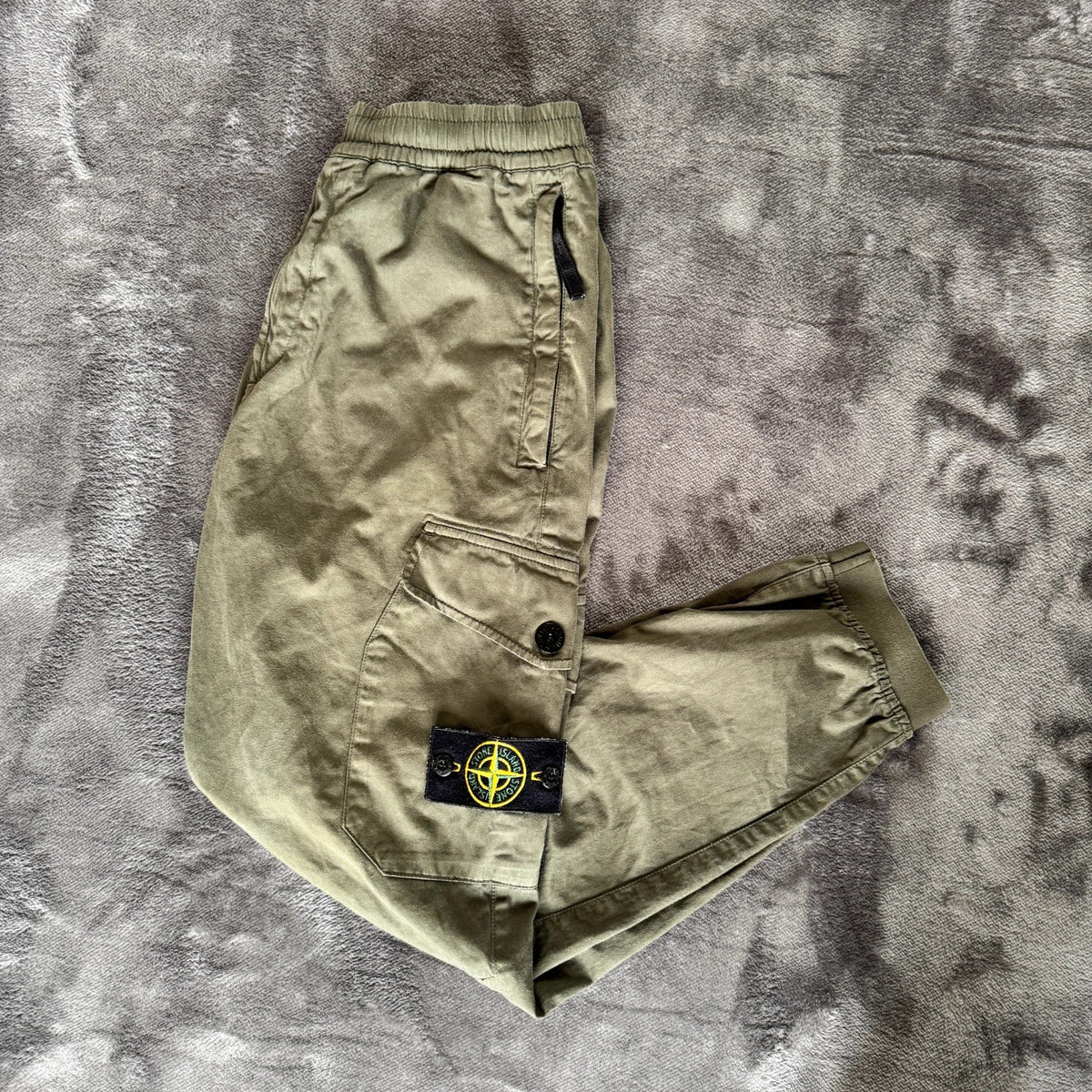 Stone Island khaki cuffed cargo trousers with logo patch and multiple pockets.