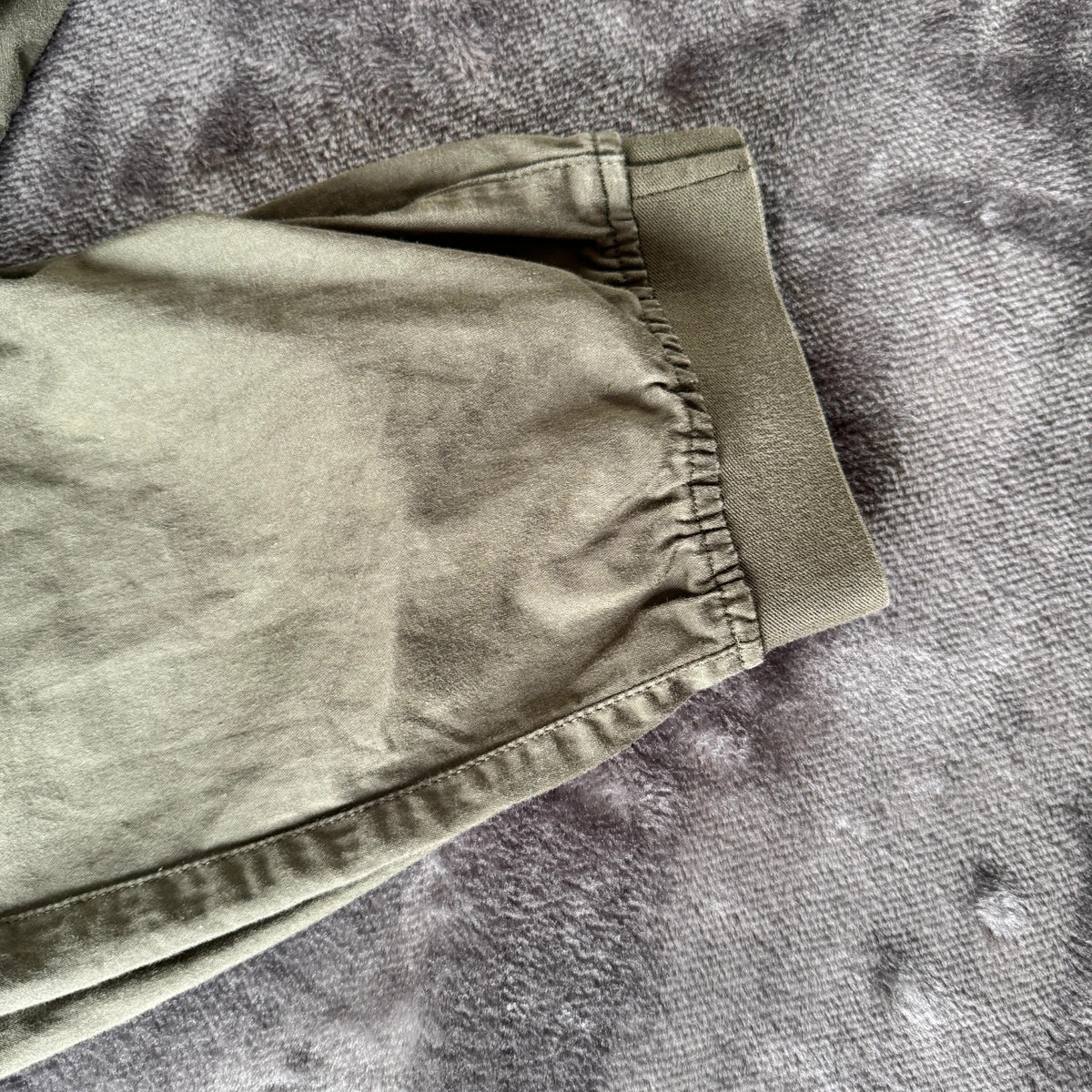 Stone Island khaki cuffed cargo trousers with logo patch and multiple pockets.