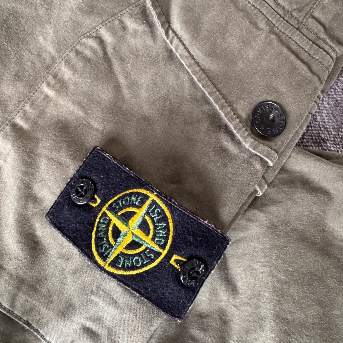 Stone Island khaki cuffed cargo trousers with logo patch and multiple pockets.