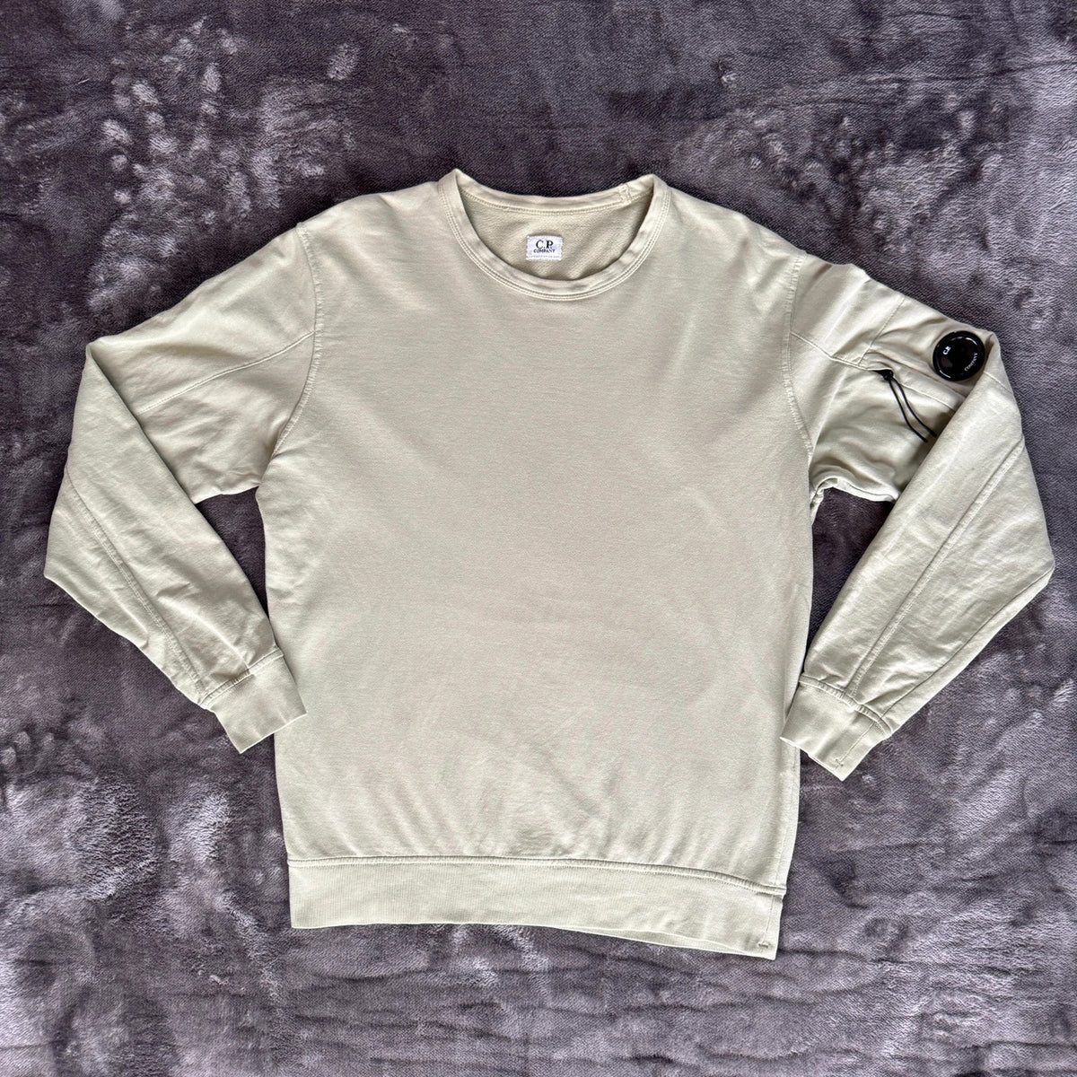 C.P. Company green sweatshirt with ribbed hem and signature goggle lens detail.