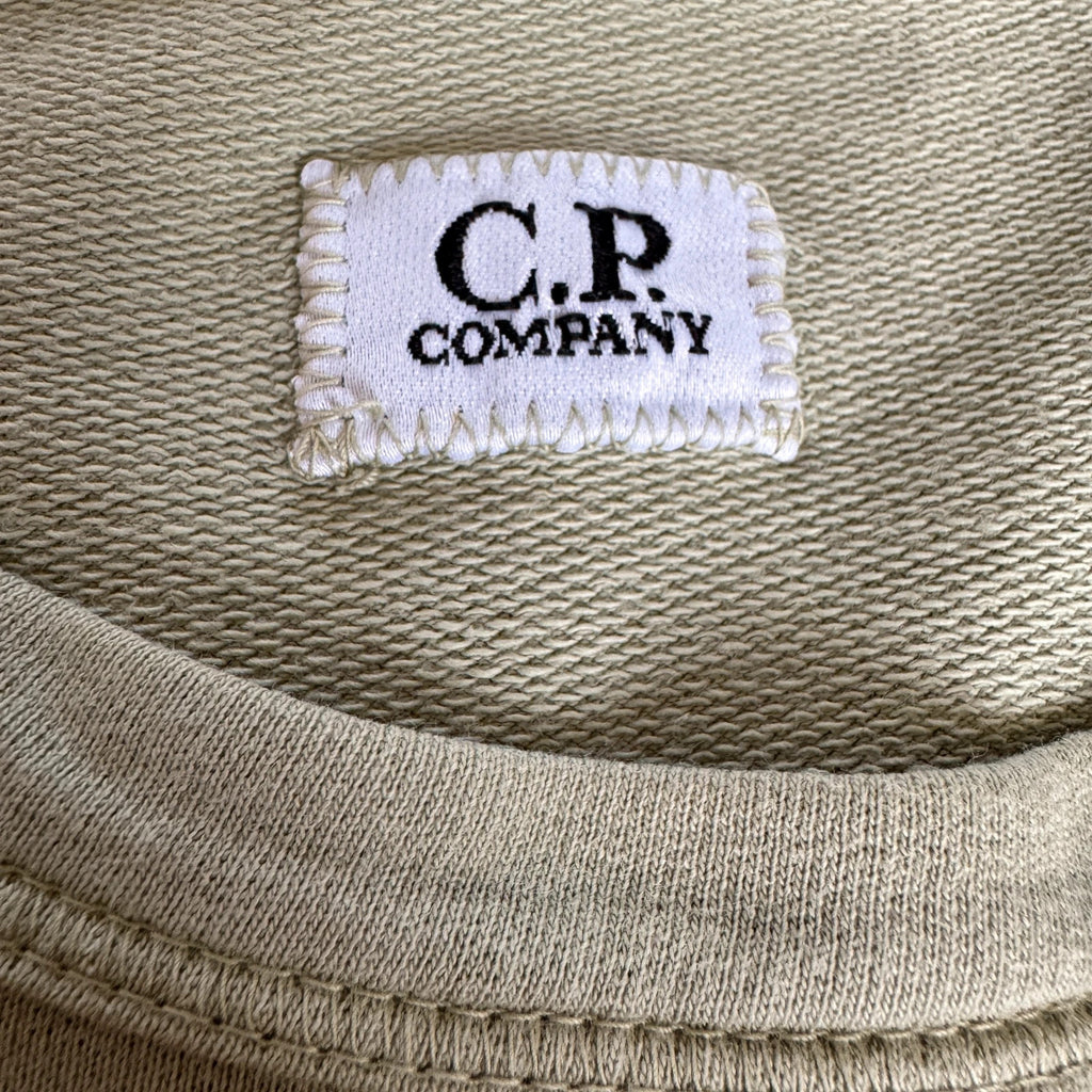 C.P. Company green sweatshirt with ribbed hem and signature goggle lens detail.