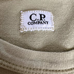 C.P. Company green sweatshirt with ribbed hem and signature goggle lens detail.