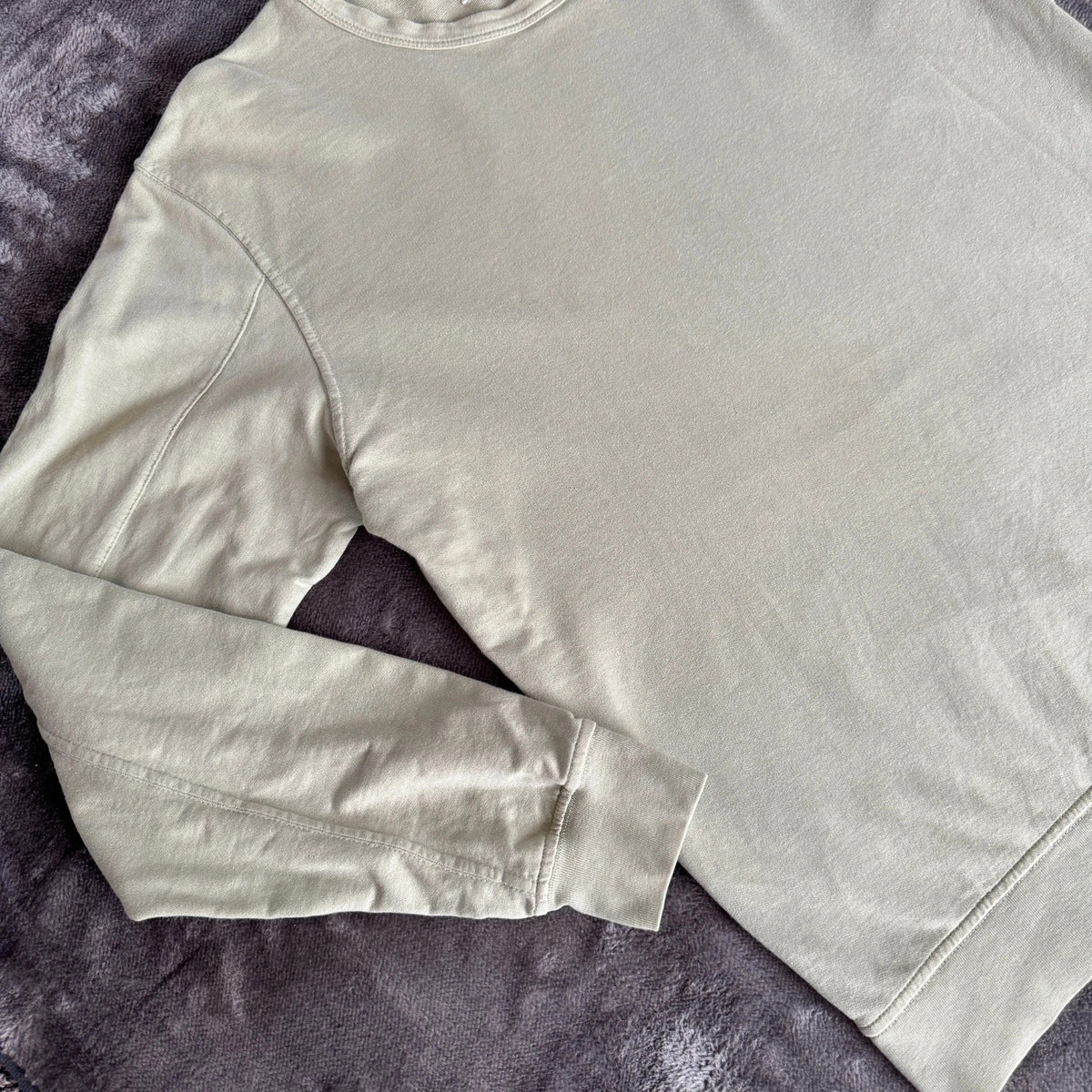 C.P. Company green sweatshirt with ribbed hem and signature goggle lens detail.