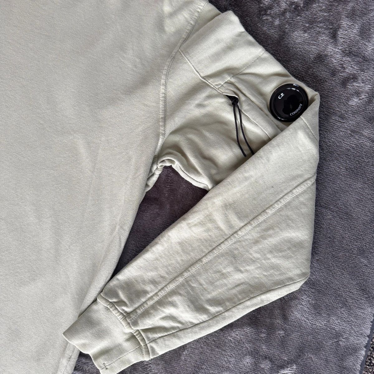 C.P. Company green sweatshirt with ribbed hem and signature goggle lens detail.