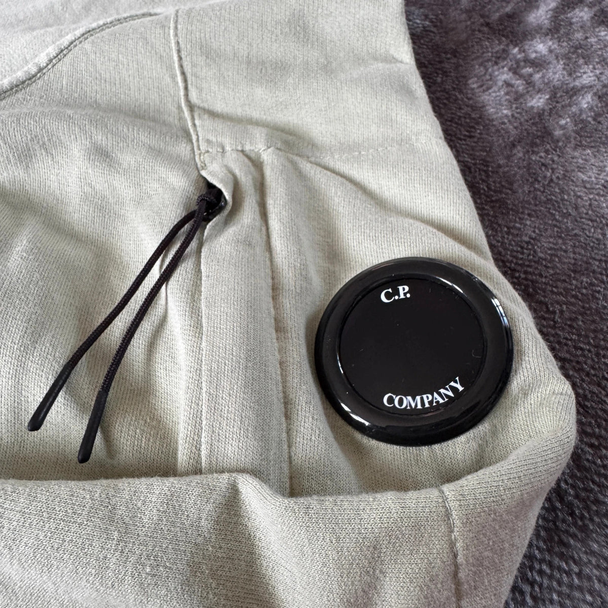 C.P. Company green sweatshirt with ribbed hem and signature goggle lens detail.