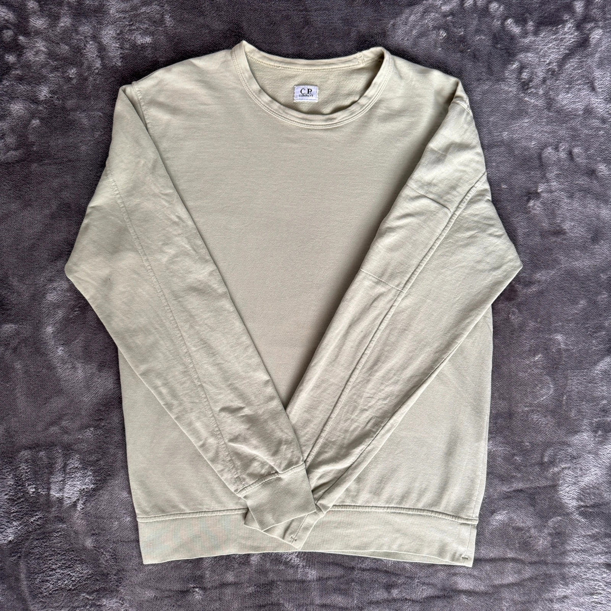 C.P. Company green sweatshirt with ribbed hem and signature goggle lens detail.