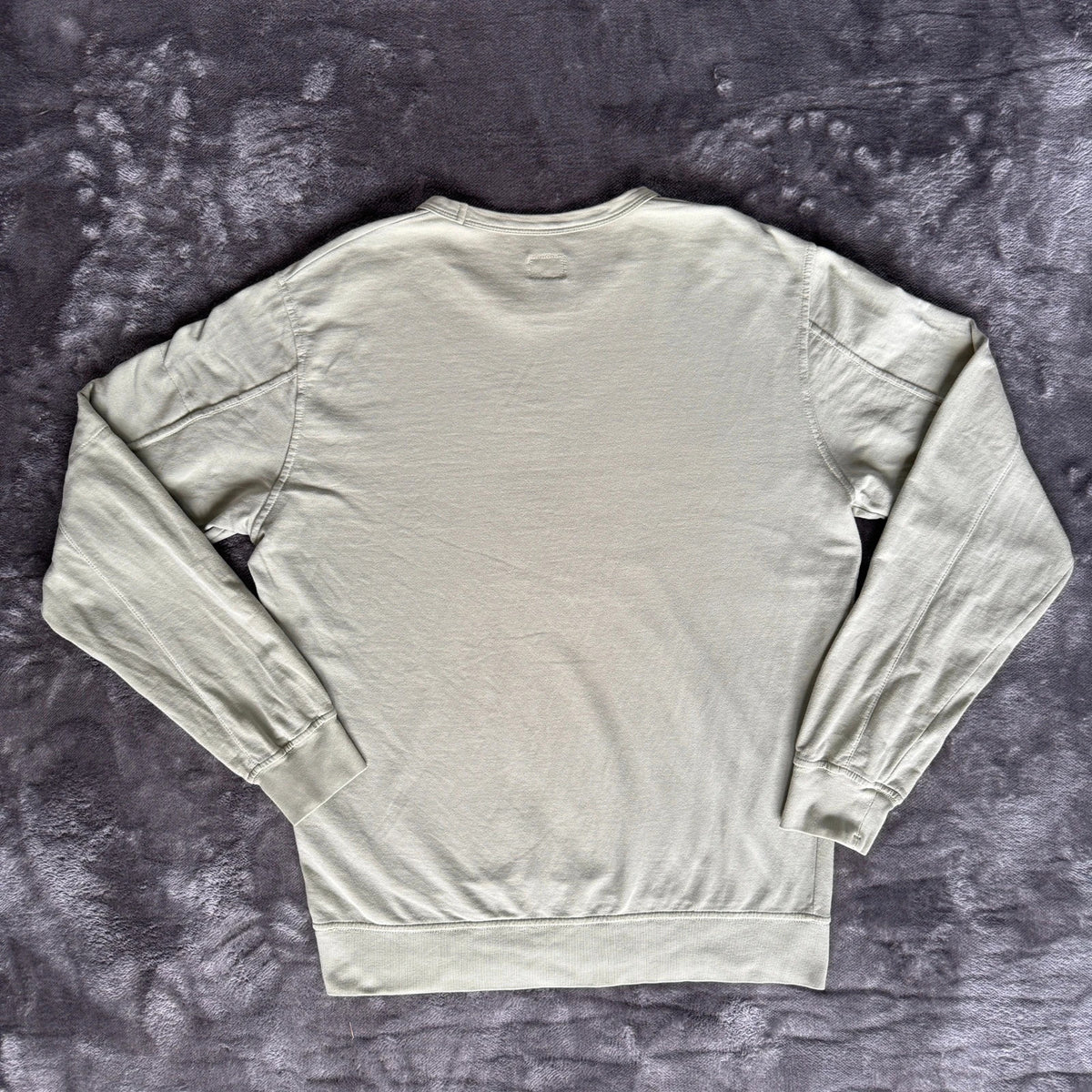 C.P. Company green sweatshirt with ribbed hem and signature goggle lens detail.