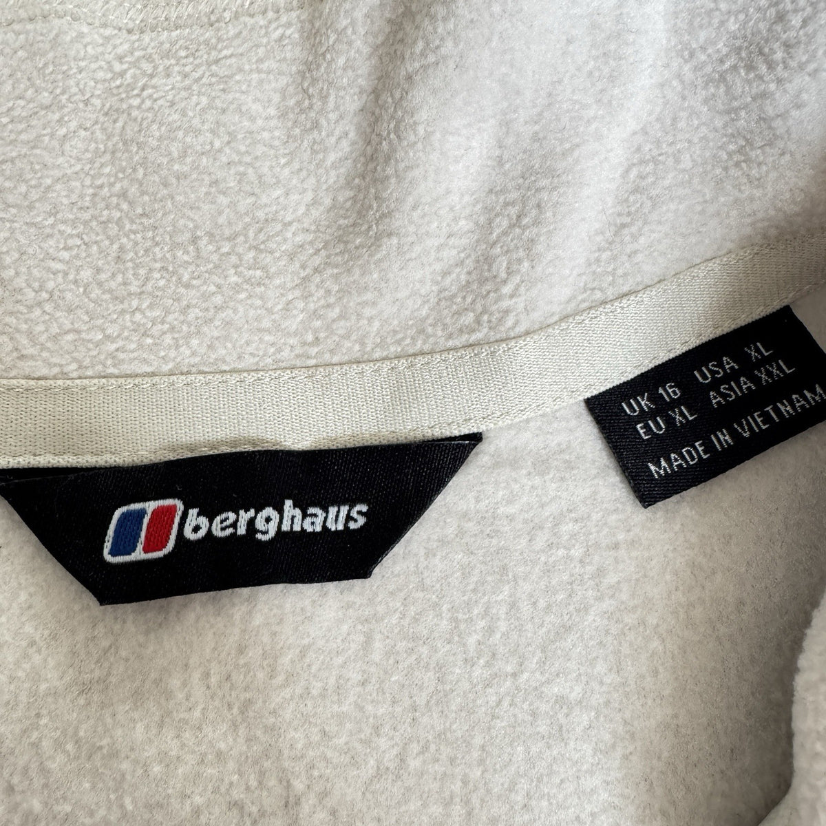 Berghaus off-white half-zip fleece with black logo pocket and stand-up collar.