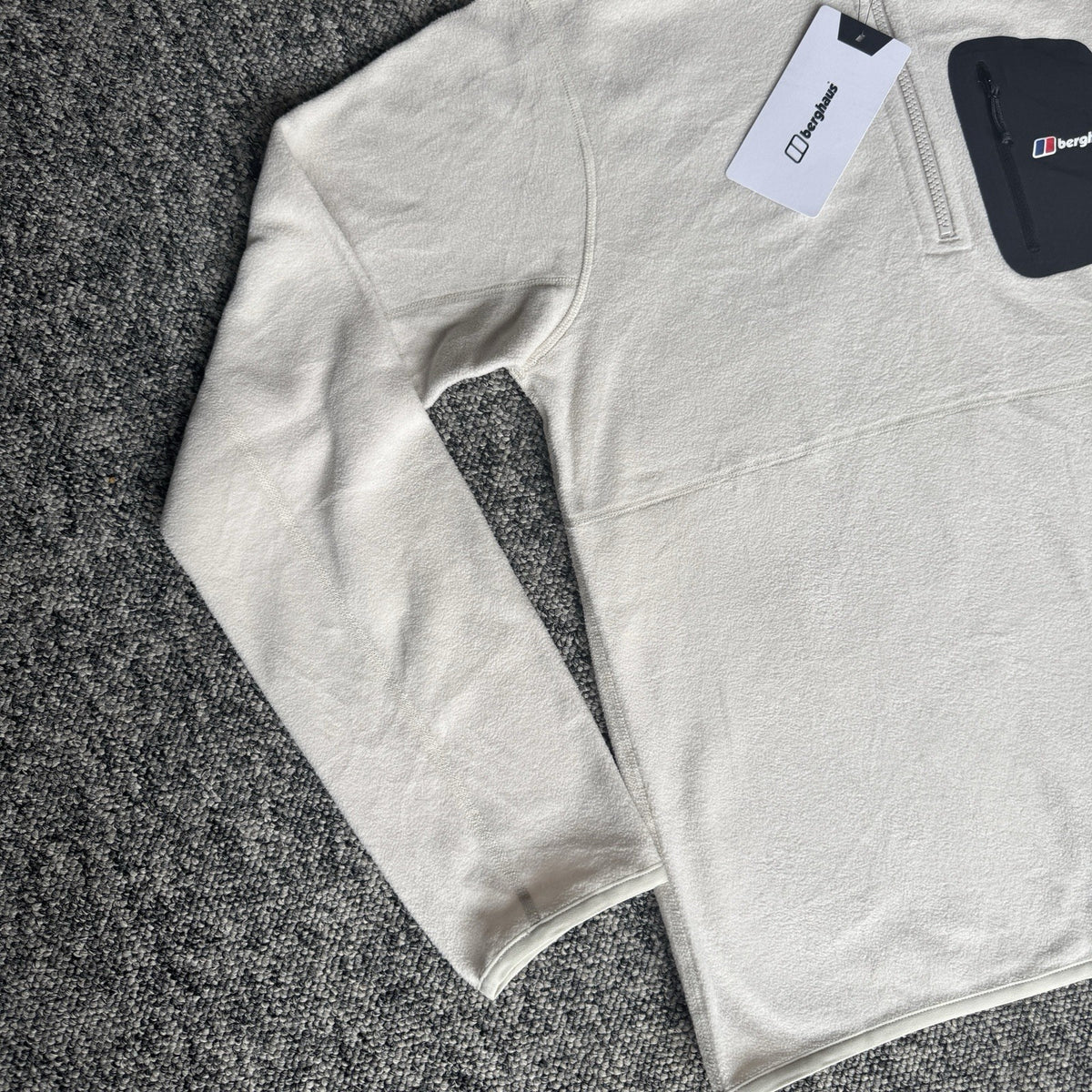 Berghaus off-white half-zip fleece with black logo pocket and stand-up collar.