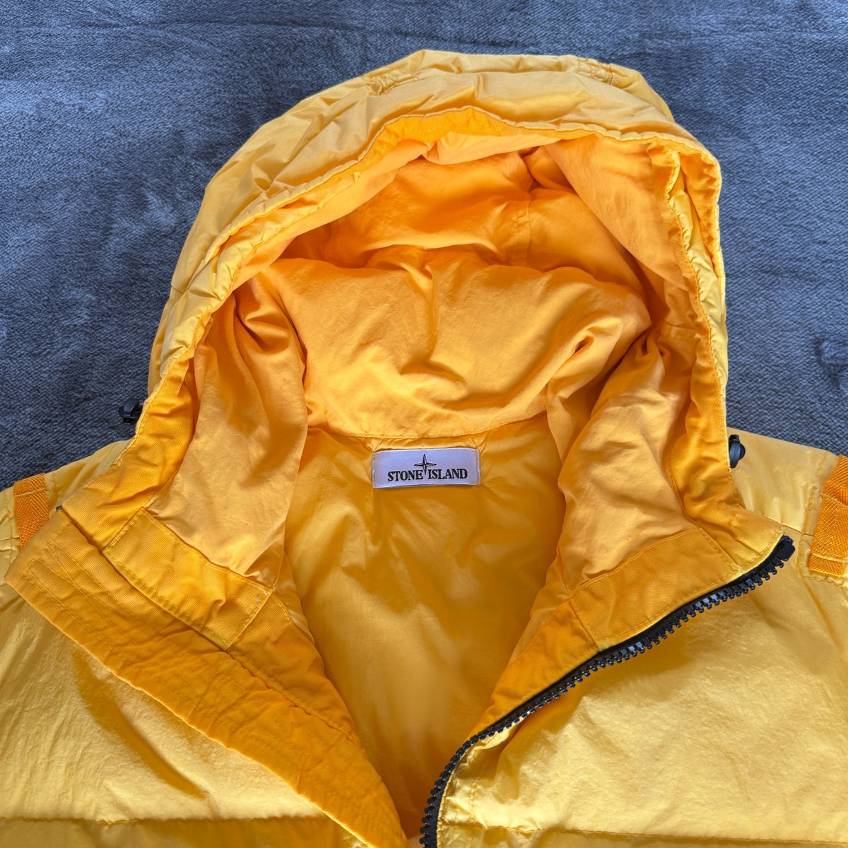 Stone Island yellow down jacket with crinkle reps texture and iconic compass logo.