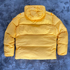 Stone Island yellow down jacket with crinkle reps texture and iconic compass logo.
