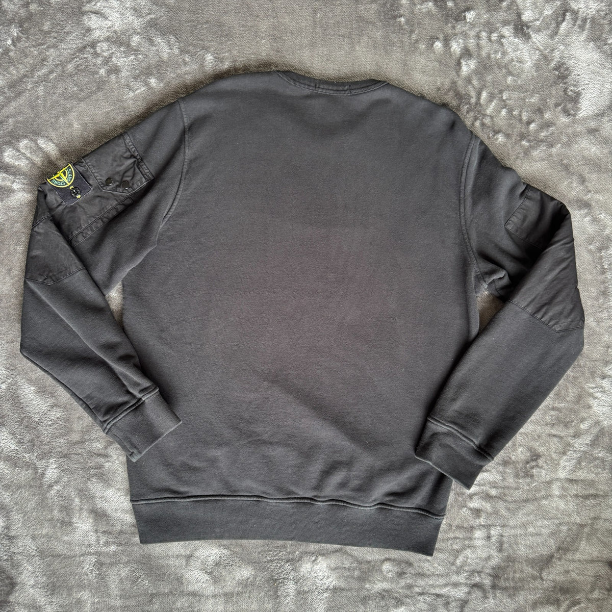 Stone Island black crewneck sweatshirt with zipped pocket and iconic compass logo.