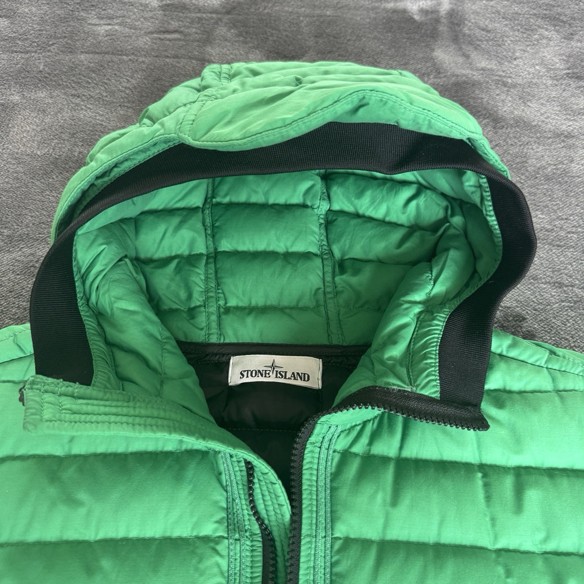Stone Island green down jacket with logo patch and 0-cotton/R-nylon material.