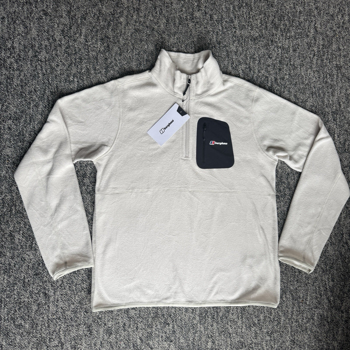 Berghaus off-white half-zip fleece with black logo pocket and stand-up collar.
