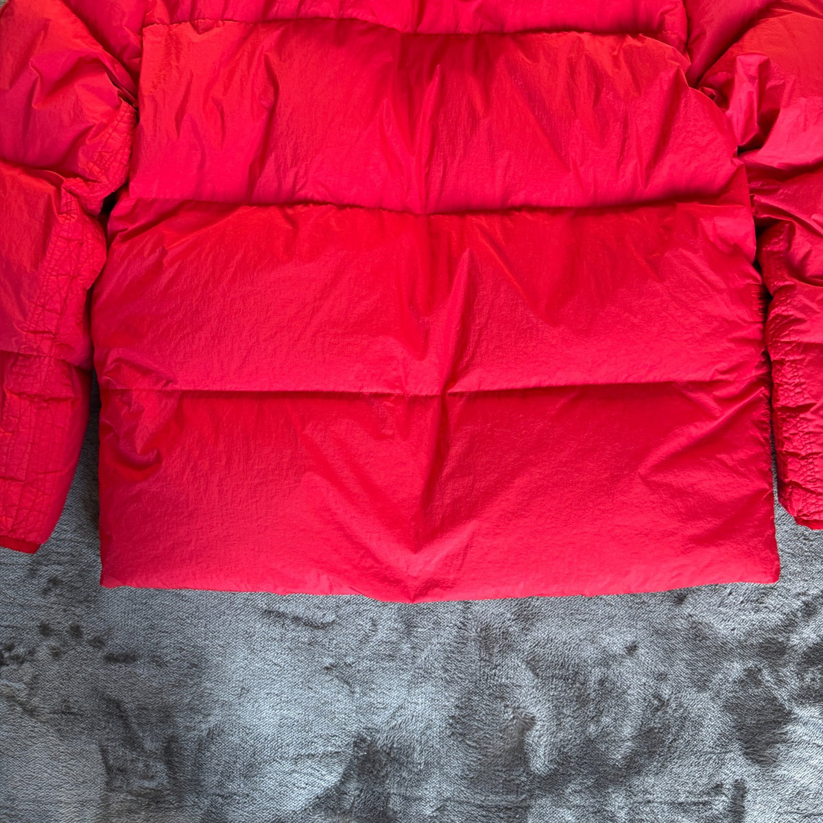 Stone Island red puffer jacket with compass patch, adjustable hood, and multiple pockets.