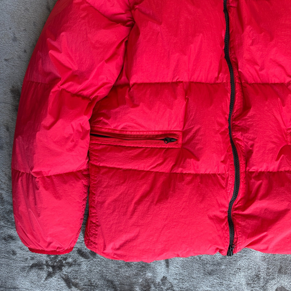 Stone Island red puffer jacket with compass patch, adjustable hood, and multiple pockets.