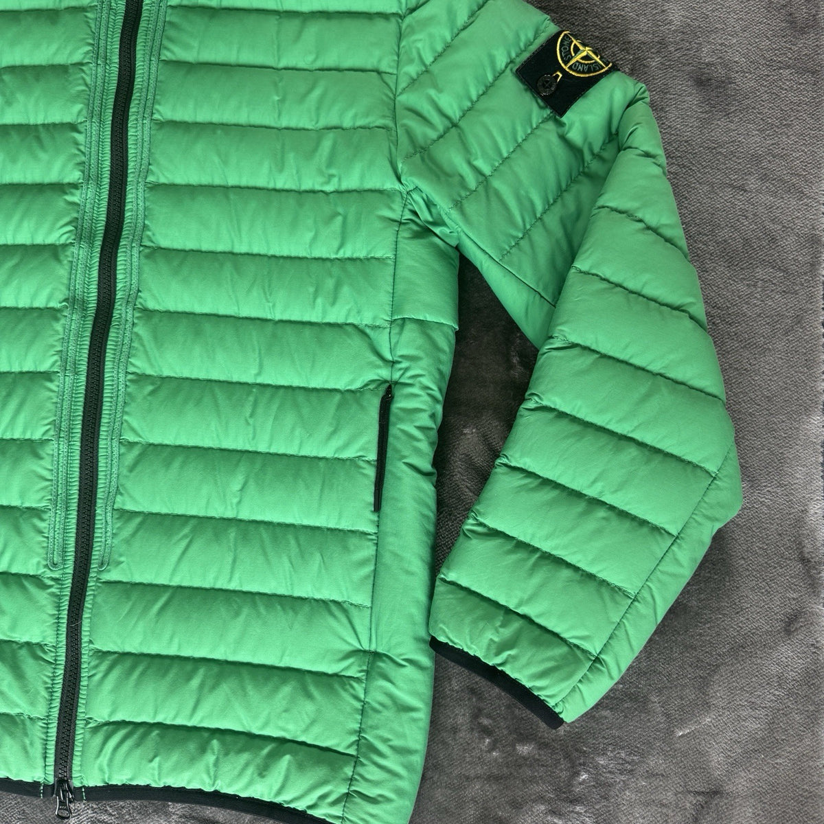Stone Island green down jacket with logo patch and 0-cotton/R-nylon material.