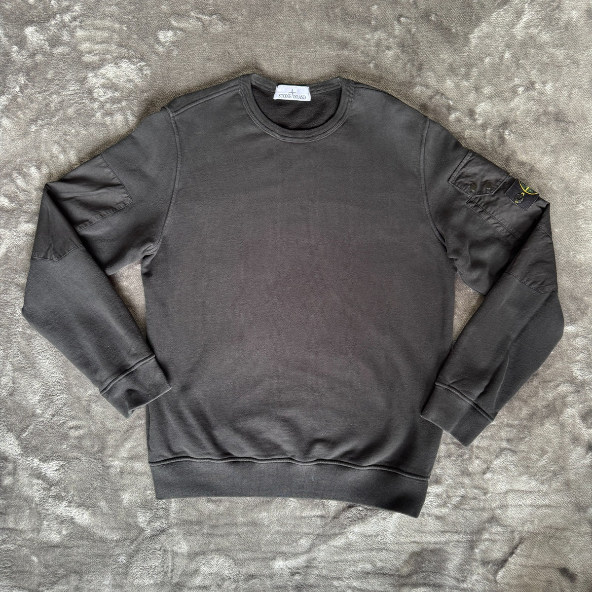Stone Island black crewneck sweatshirt with zipped pocket and iconic compass logo.