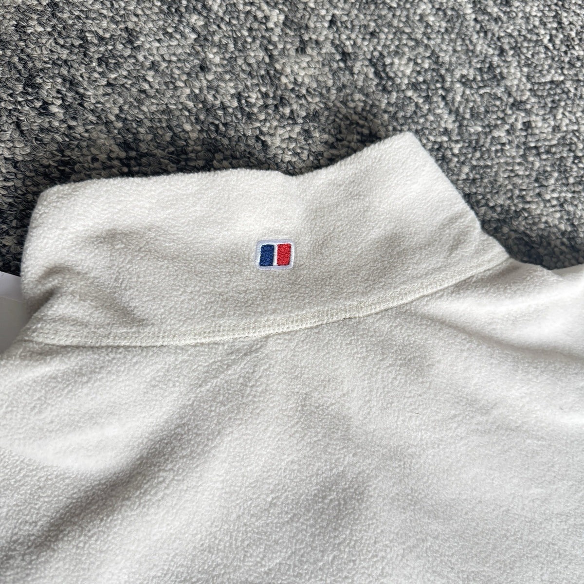 Berghaus off-white half-zip fleece with black logo pocket and stand-up collar.