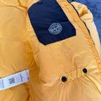 Stone Island yellow down jacket with crinkle reps texture and iconic compass logo.