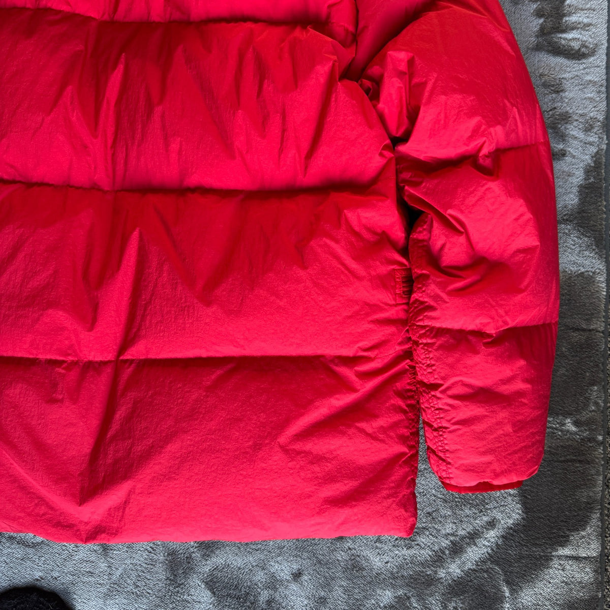 Stone Island red puffer jacket with compass patch, adjustable hood, and multiple pockets.