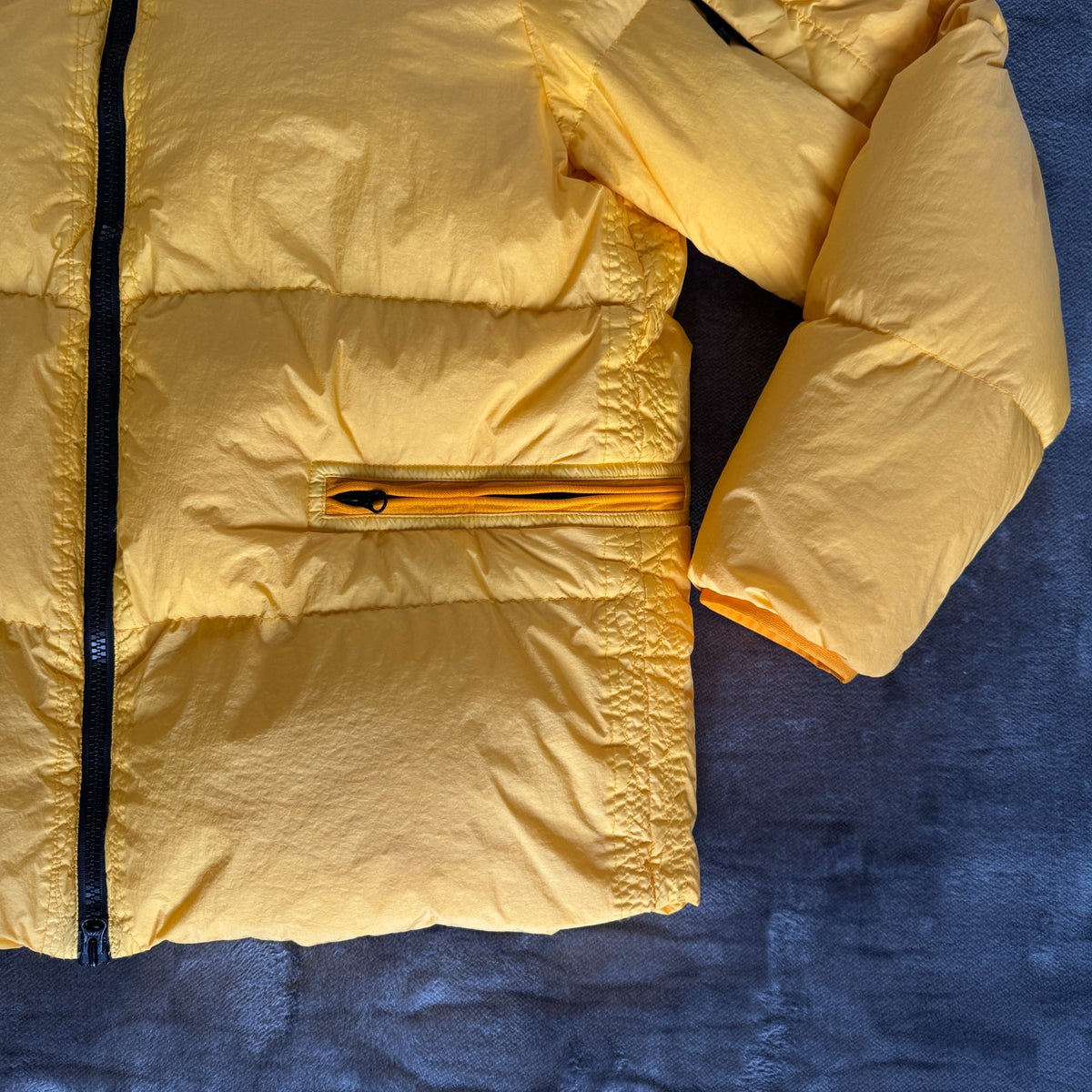 Stone Island yellow down jacket with crinkle reps texture and iconic compass logo.