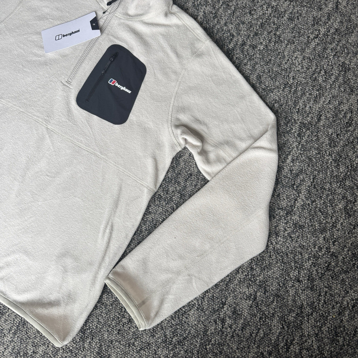 Berghaus off-white half-zip fleece with black logo pocket and stand-up collar.