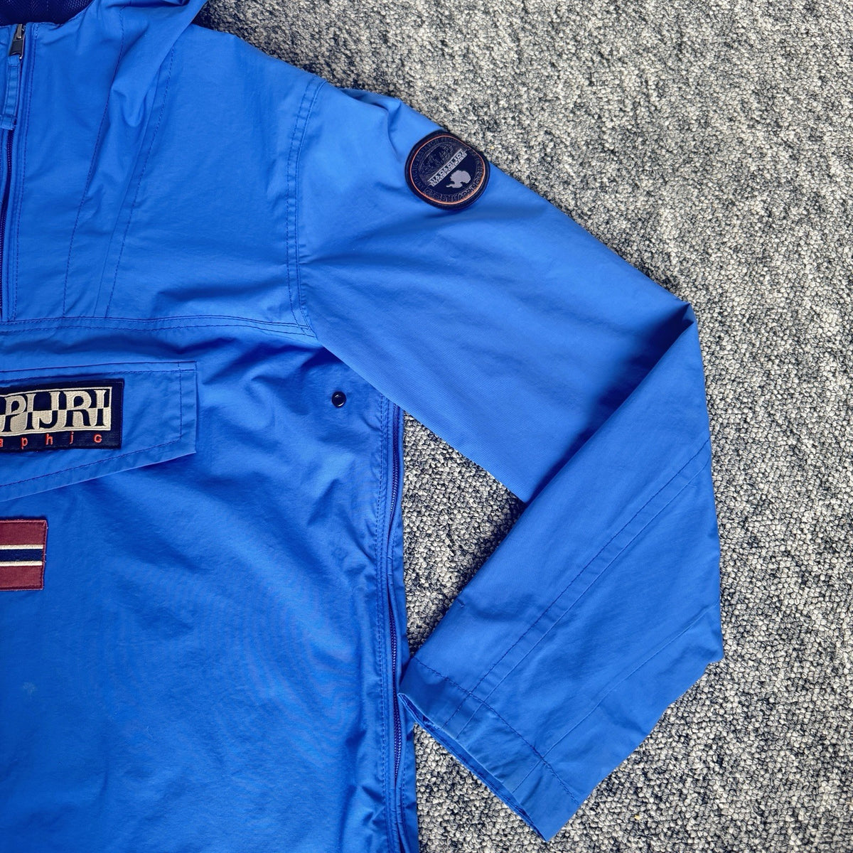Napapijri blue anorak jacket with logo chest flap and quarter-zip front closure.