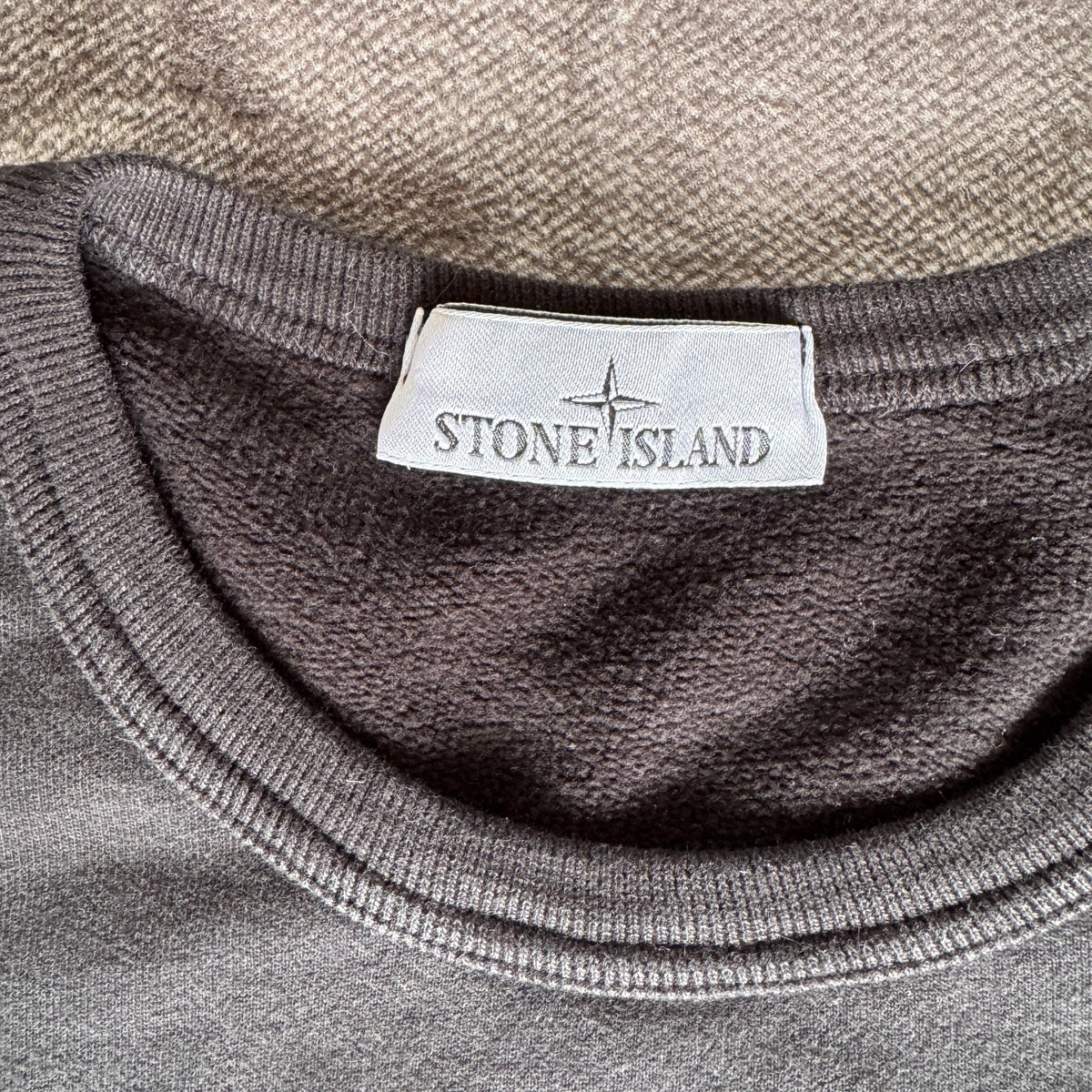 Stone Island black crewneck sweatshirt with zipped pocket and iconic compass logo.