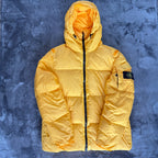 Stone Island yellow down jacket with crinkle reps texture and iconic compass logo.