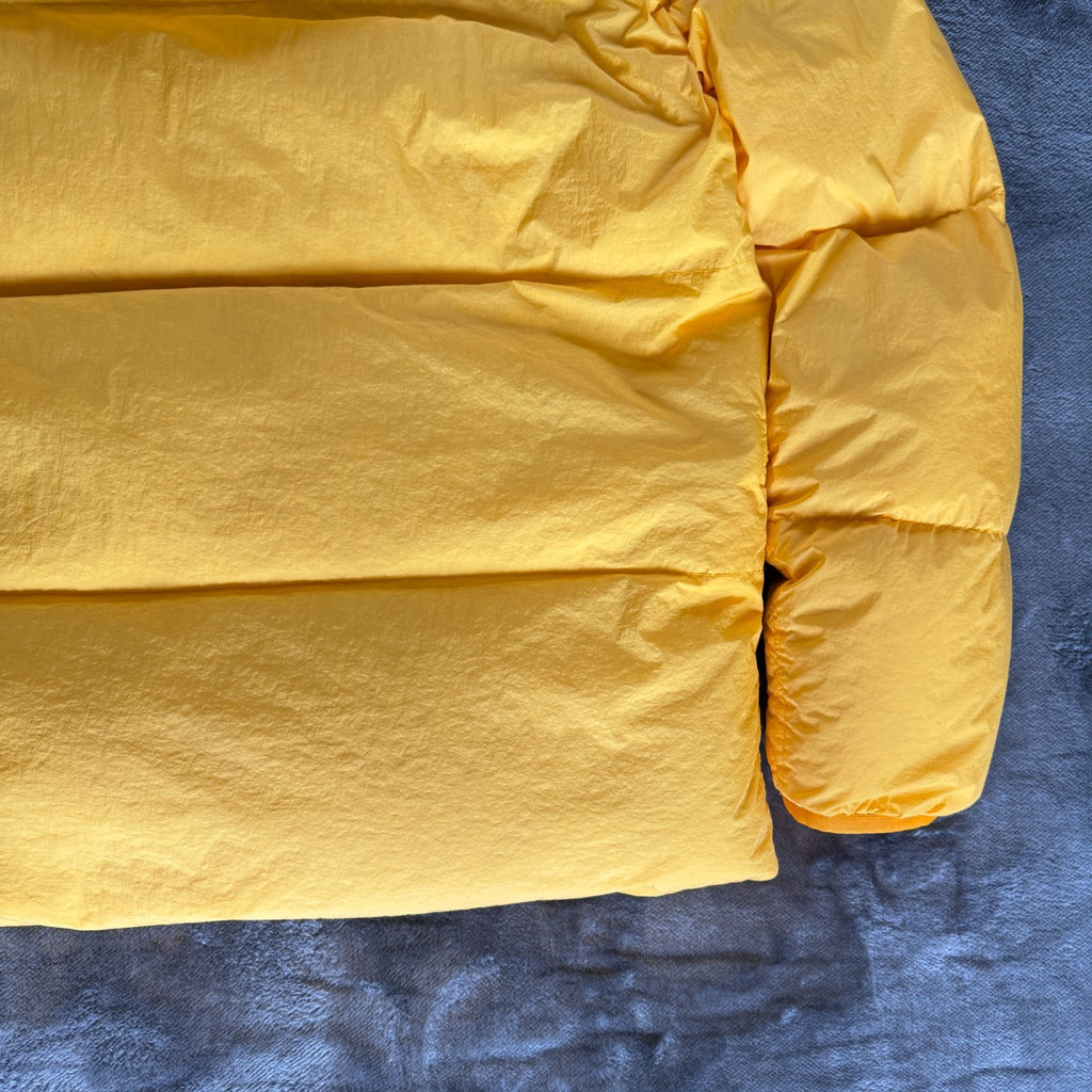 Stone Island yellow down jacket with crinkle reps texture and iconic compass logo.